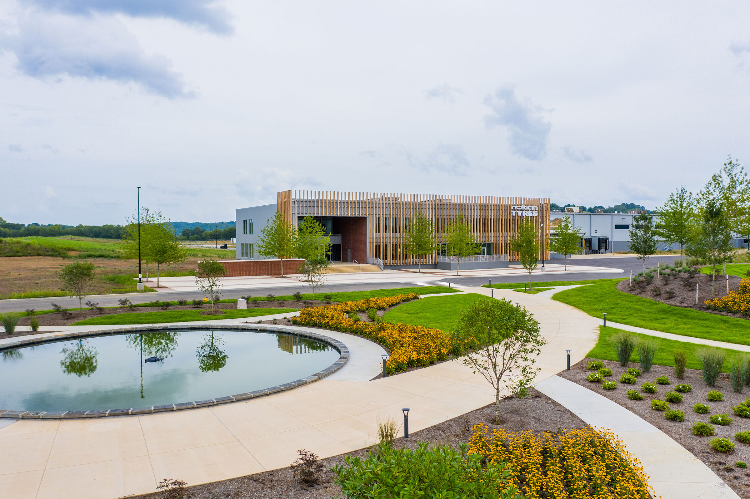 Sidewalk and pond surrounded by native plants with the Nokian building in the background